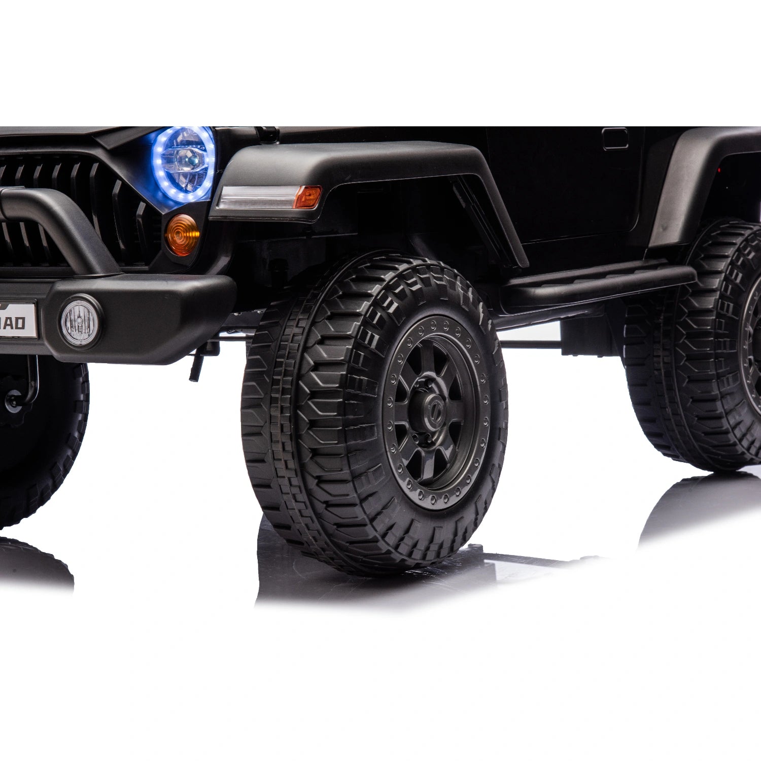 Close-up of front wheel and rugged off-road tire on black 12V Jeep-style ride-on toy car for kids with LED light.