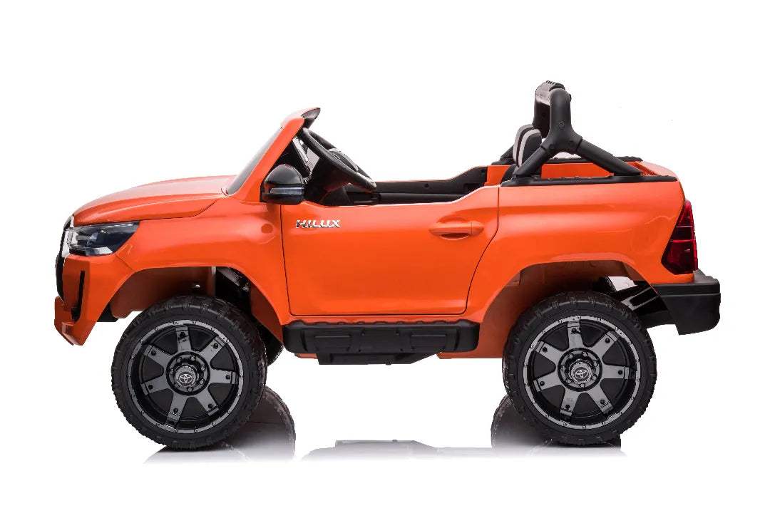 Side view of orange 24V licensed Toyota Hilux SR5 2-seater kids ride-on ute with detailed wheels and open cabin