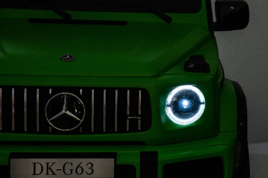 Close-up of green 24V Mercedes-AMG G63 kids ride-on car front grille with illuminated round LED headlight.