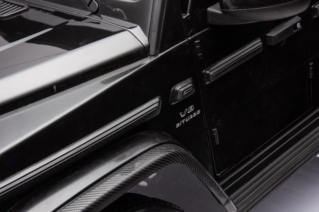 Close-up of black 24V licensed Mercedes-AMG G63 kids ride-on car showing V8 turbo badge and carbon fiber details