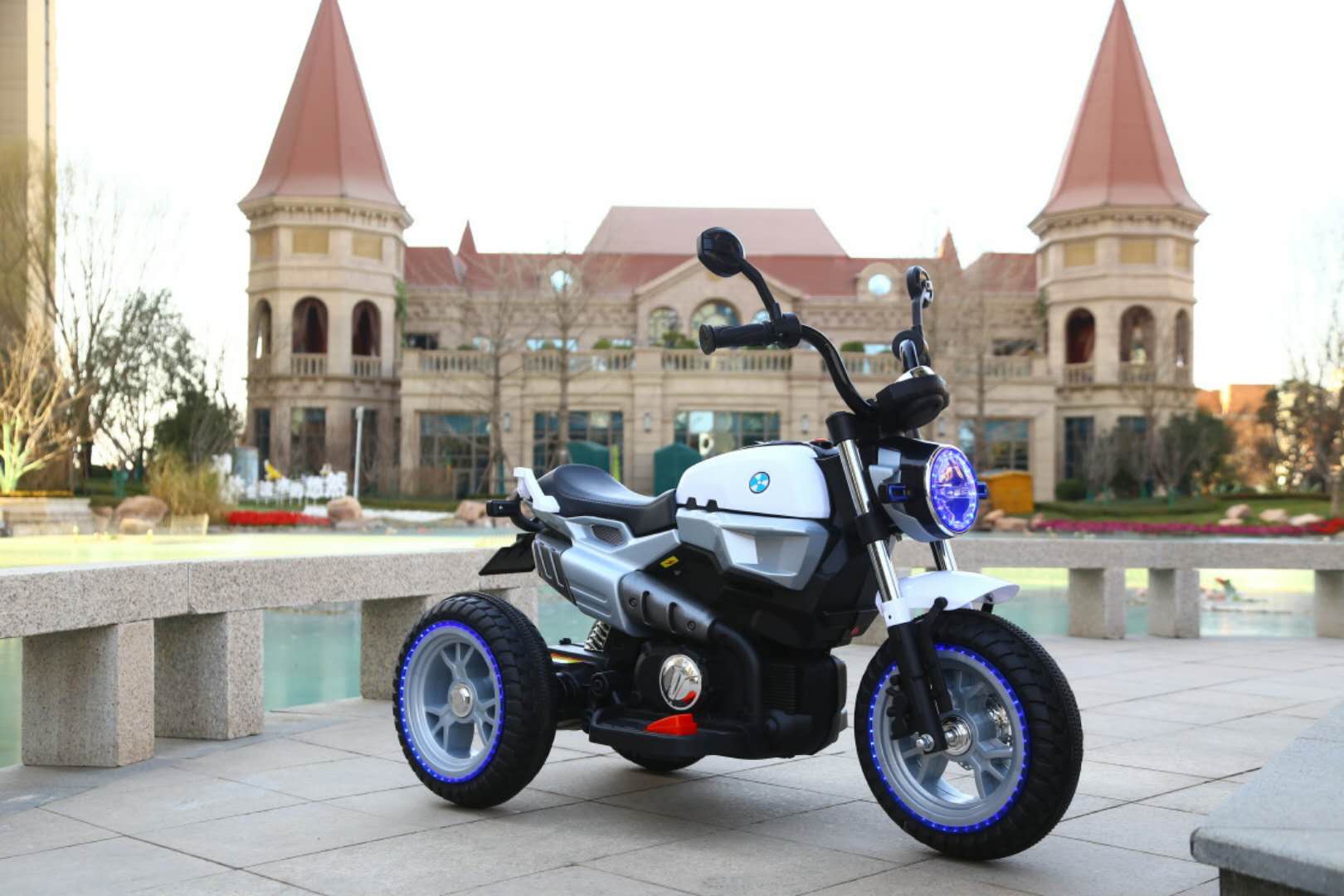 Grey 12v electric ride-on motorbike for kids with LED lights, suitable for ages 3 to 7, displayed outdoors.