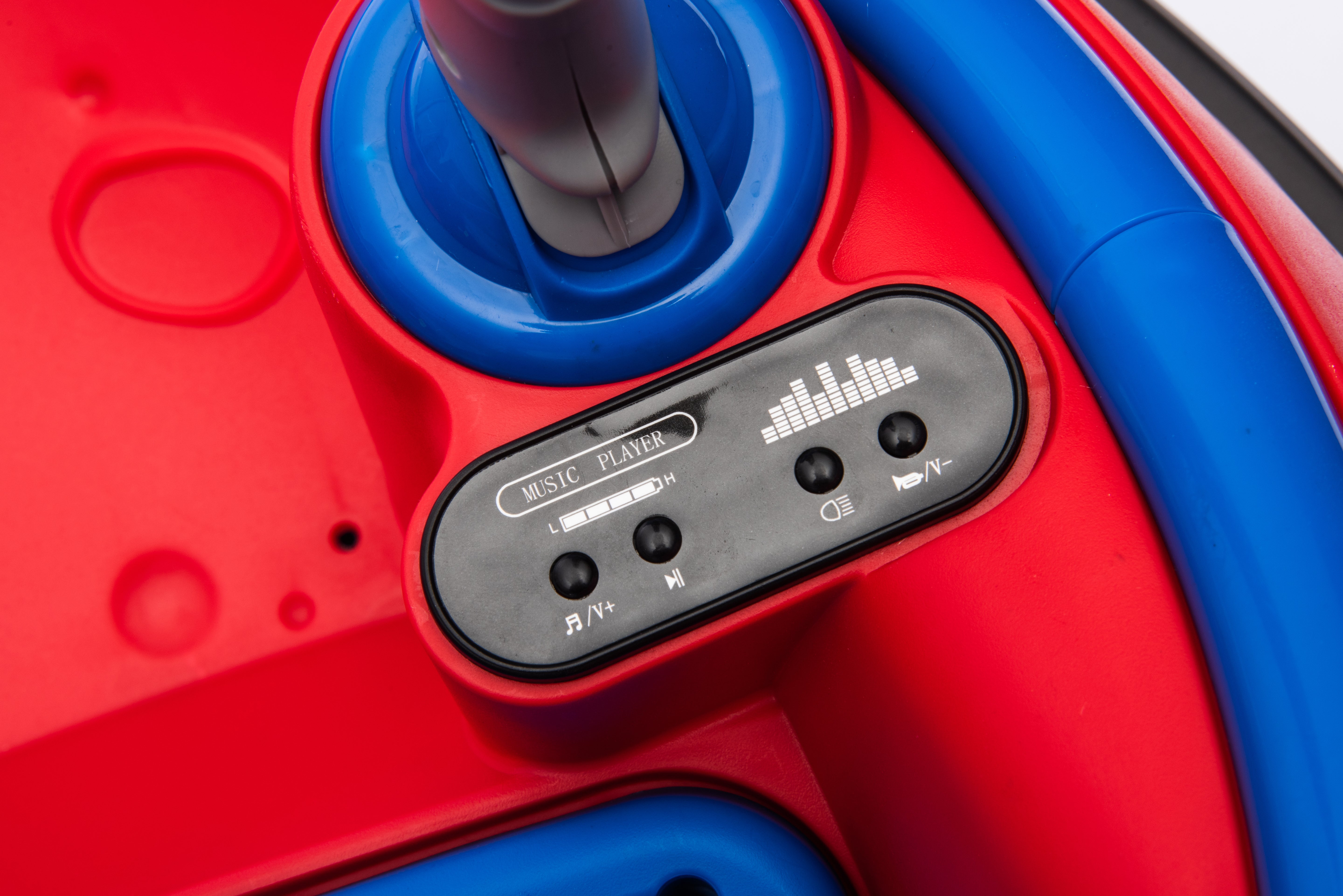 Close-up of music player control panel on red and blue 12V kids bumper car for toddlers with joystick control.