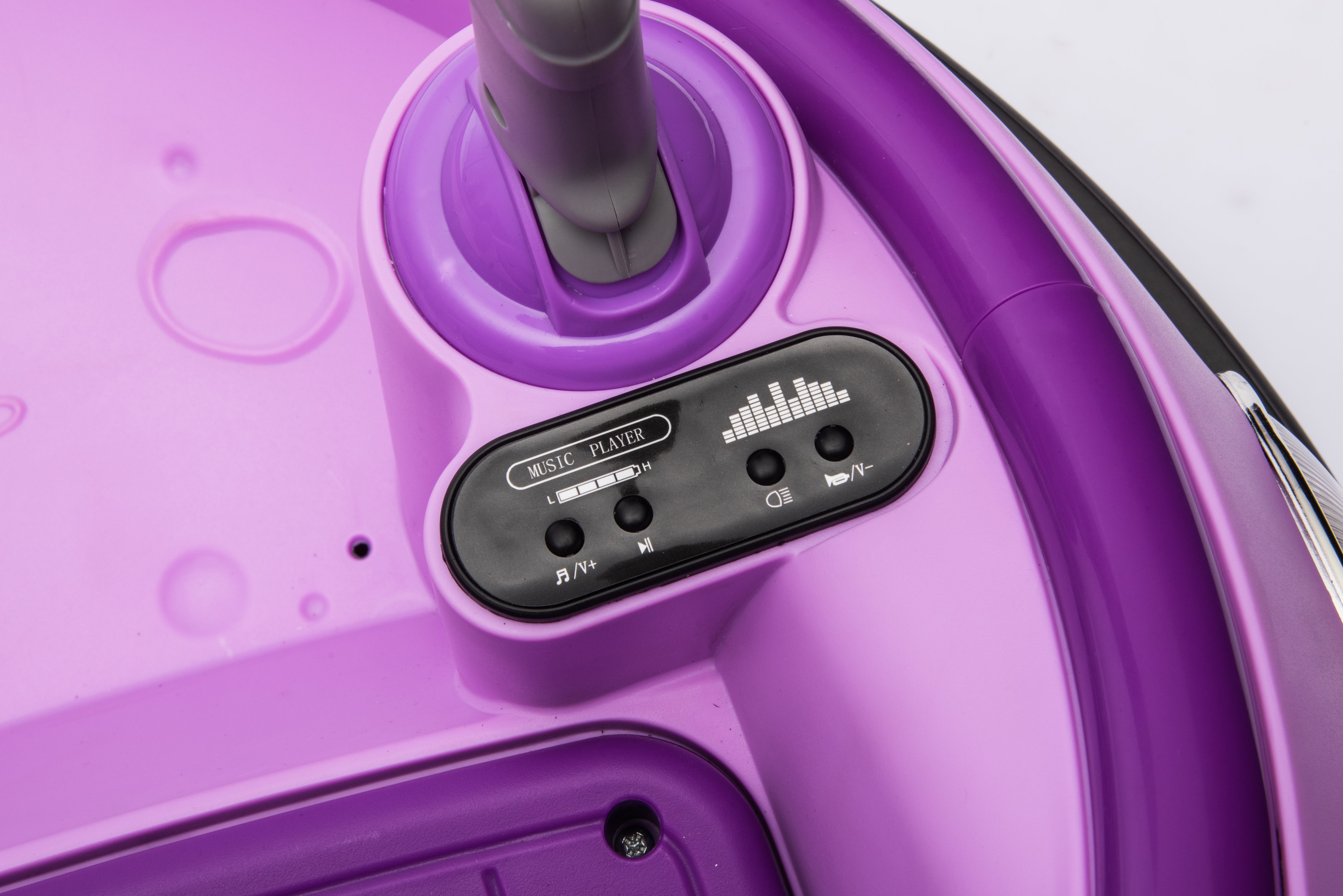Close-up of purple kids bumper car dashboard showing music player controls and handlebar detail.