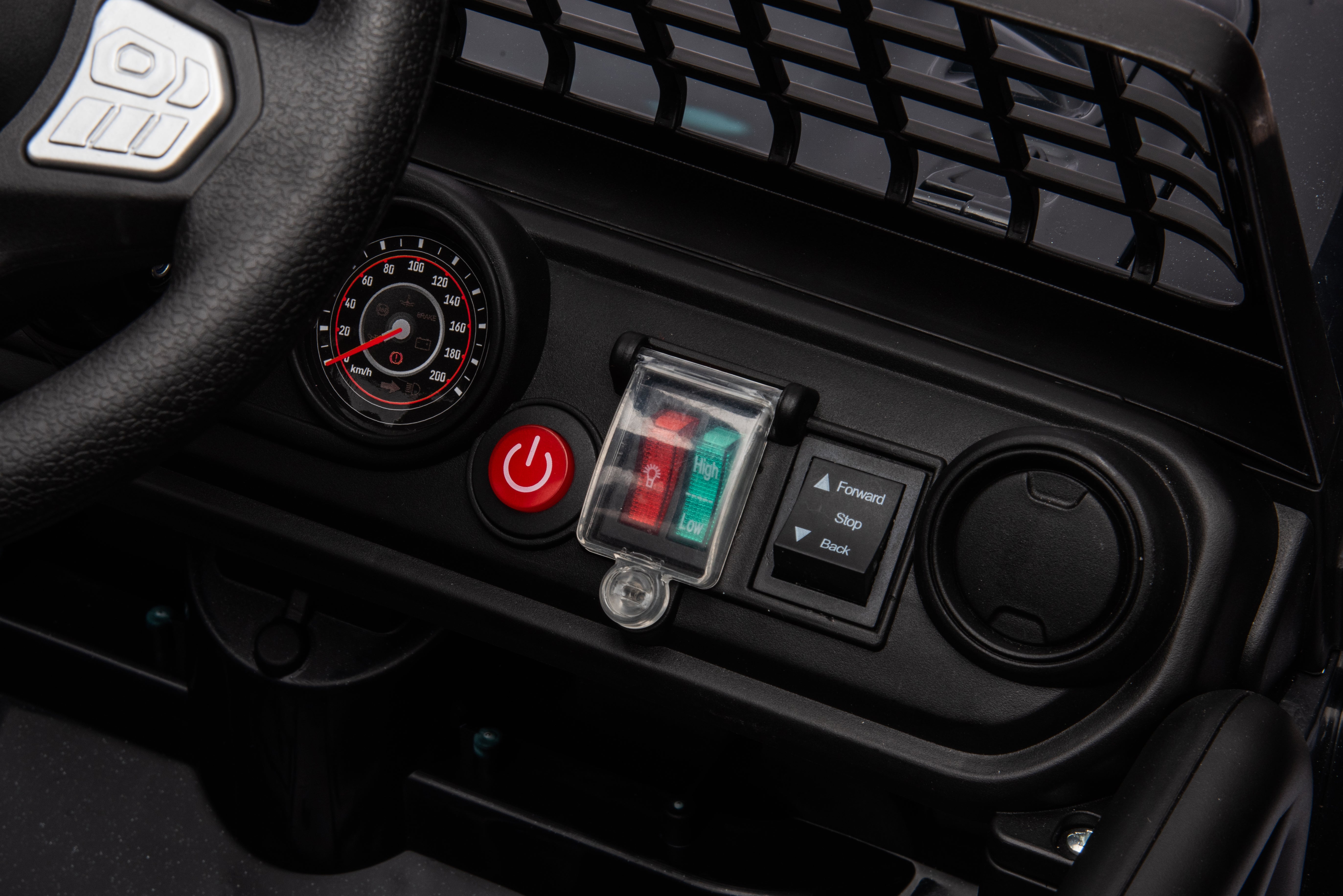 Close-up of dashboard controls and steering wheel on 12V black Jeep-style electric ride-on car for kids.