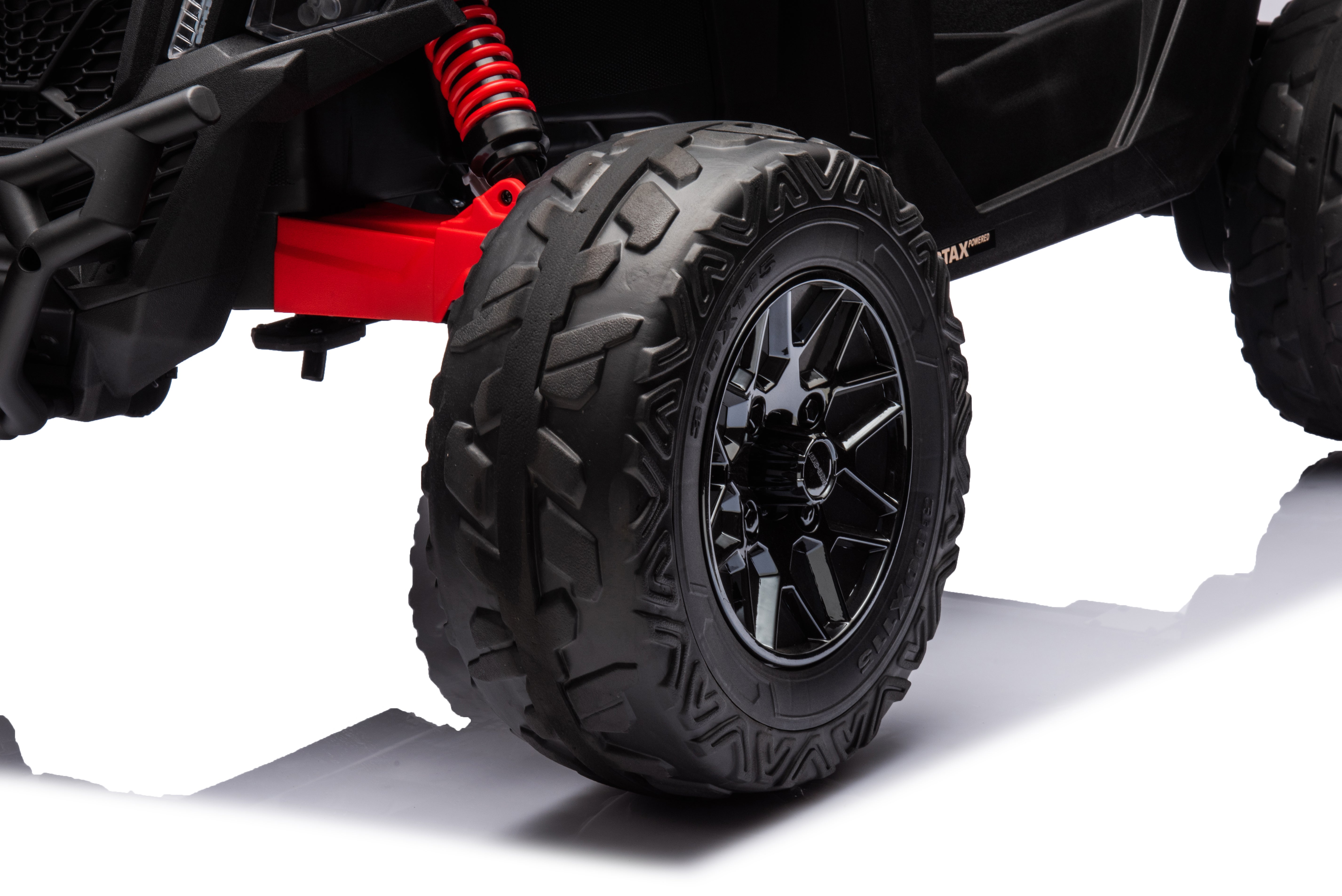 Close-up of black EVA rubber tire and red spring suspension on Can-Am Maverick 24V kids ride-on UTV wheel.
