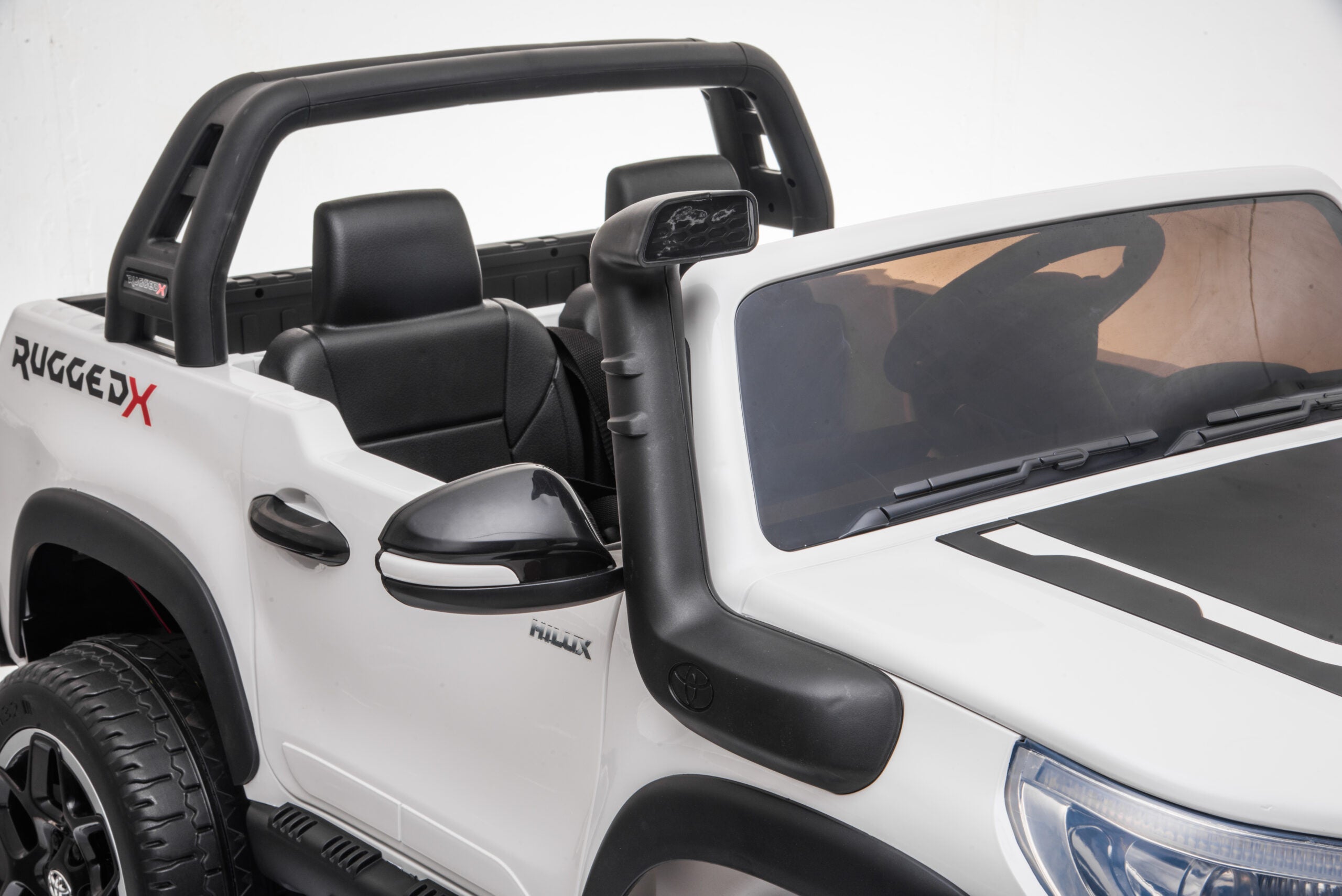 White 24v Toyota Hilux 4WD 800W ride-on electric car with black interior and off-road features for kids.