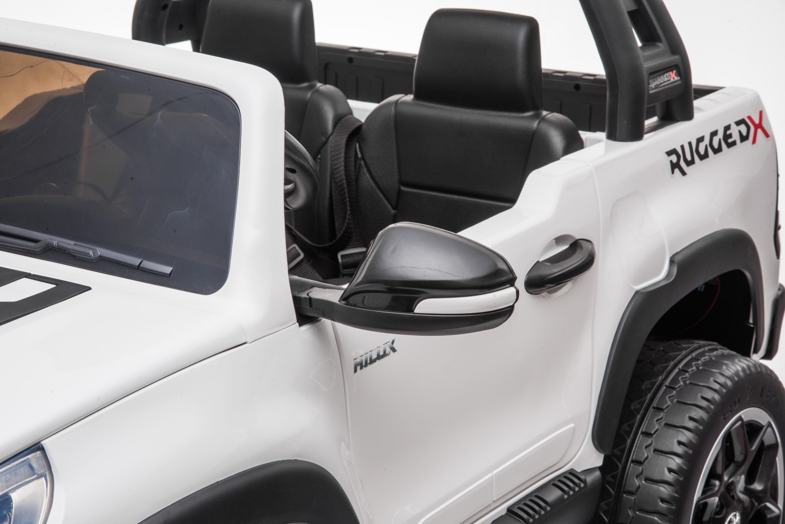 Close-up of white 24V Ride On Toyota Hilux 4WD kids electric car with black leather seats and rugged design detail.