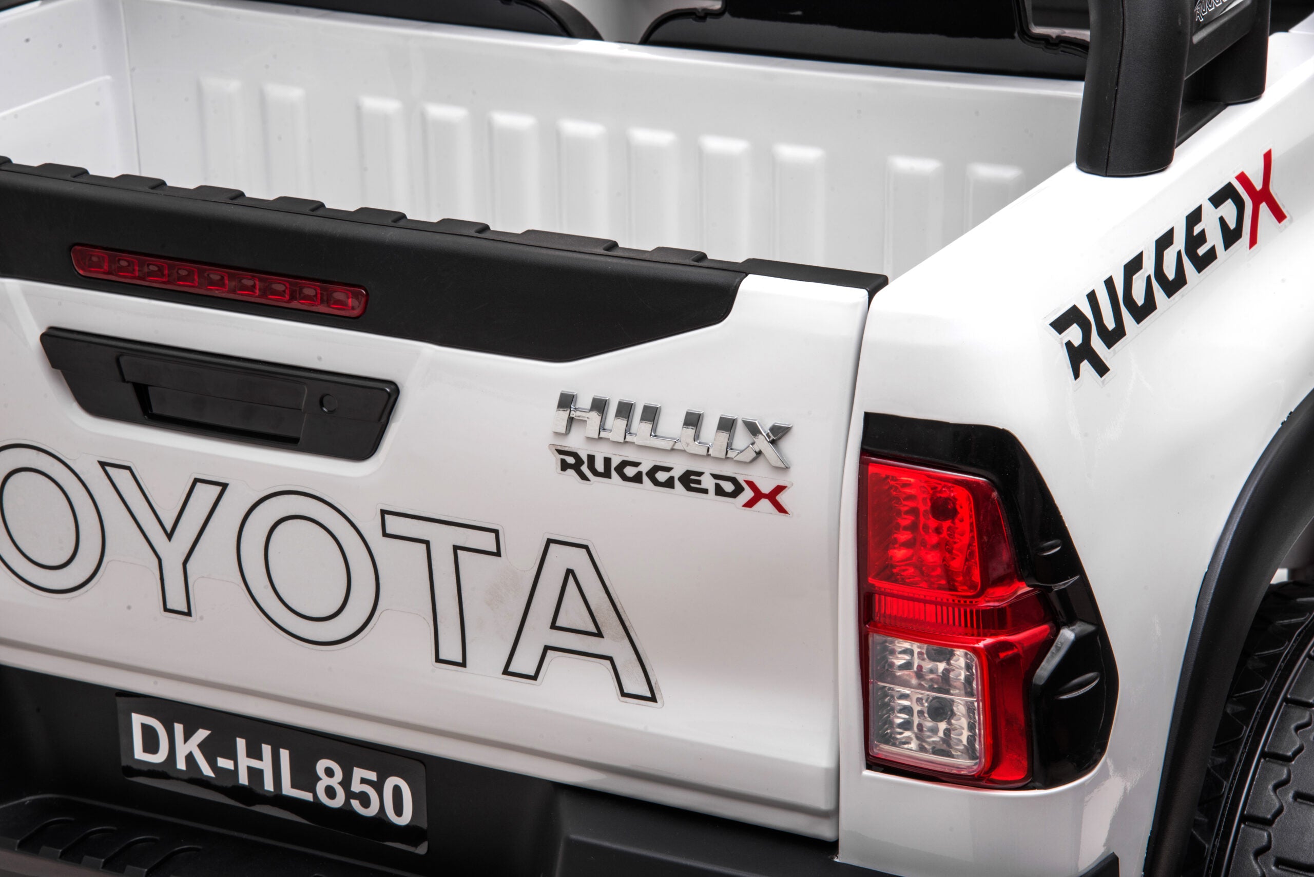 Close-up of the rear white Toyota Hilux 24V ride-on car showing rugged branding and detailed taillight design.