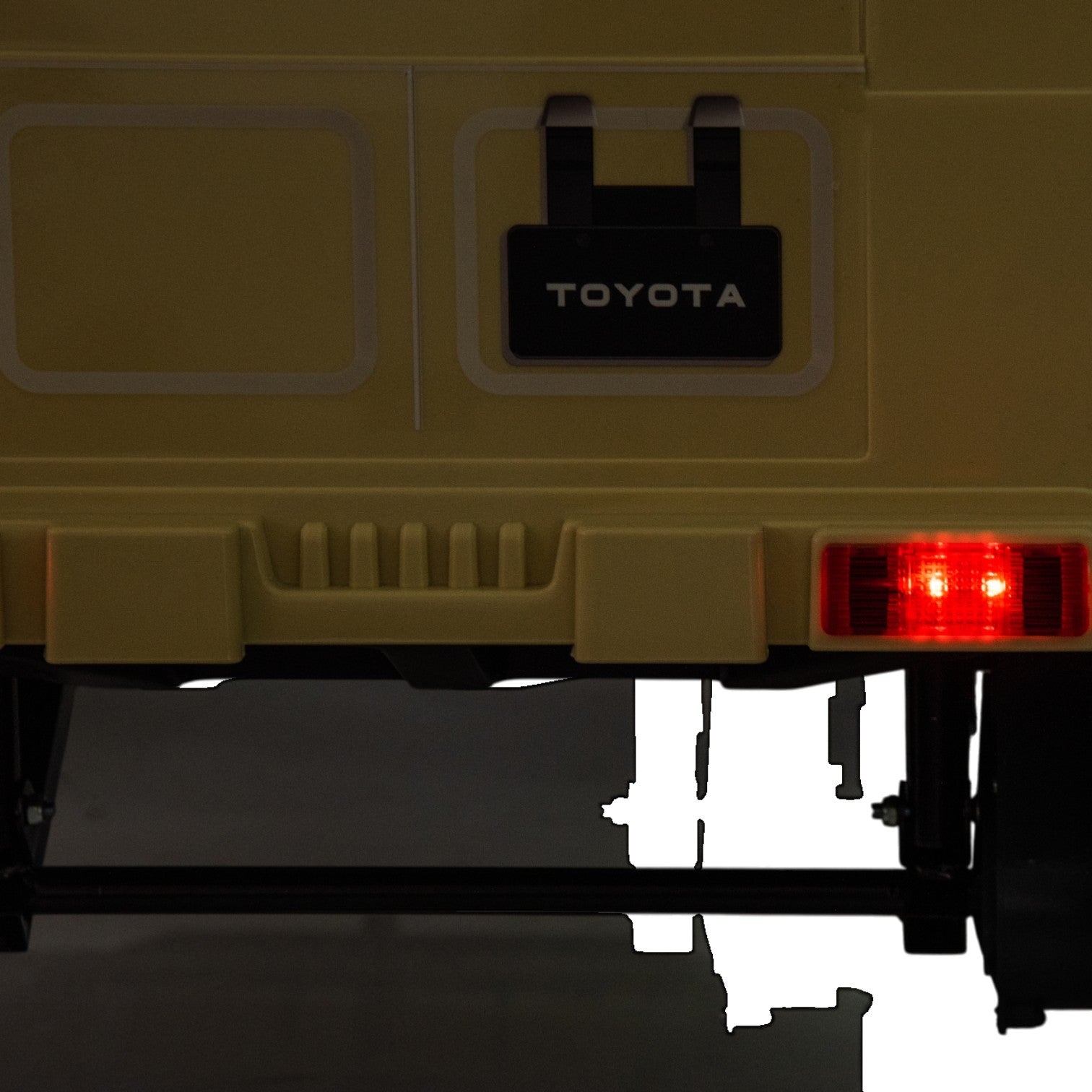Close-up of the rear of a yellow Toyota FJ Cruiser licensed electric toy car with illuminated red tail light for kids.