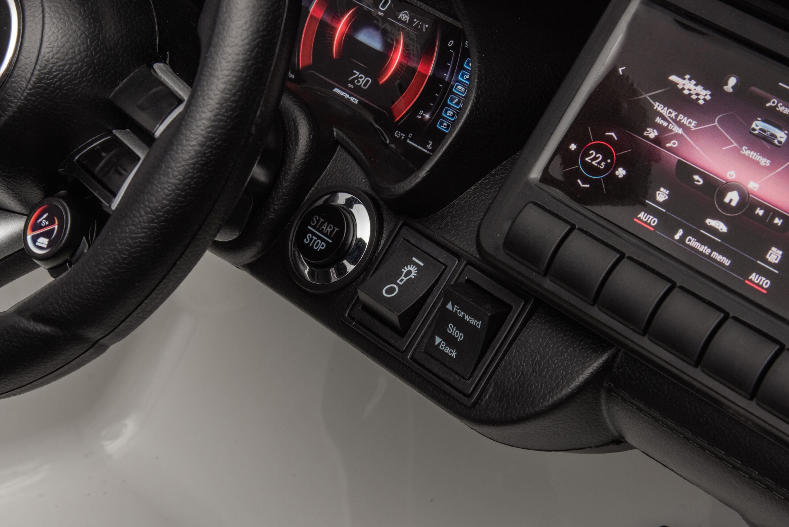 Close-up of the dashboard and steering wheel showing start button and control switches in a kids' electric ride-on car.