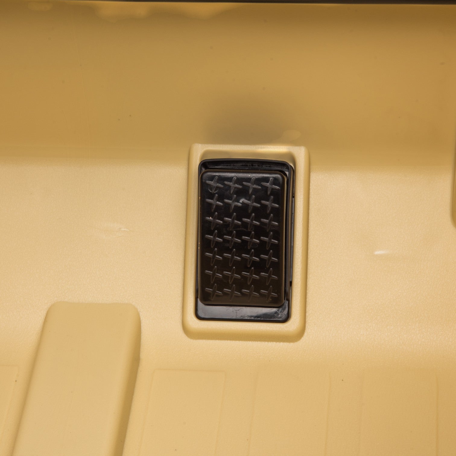 Close-up of the black accelerator pedal inside the beige interior of a Toyota FJ Cruiser electric toy car for kids.