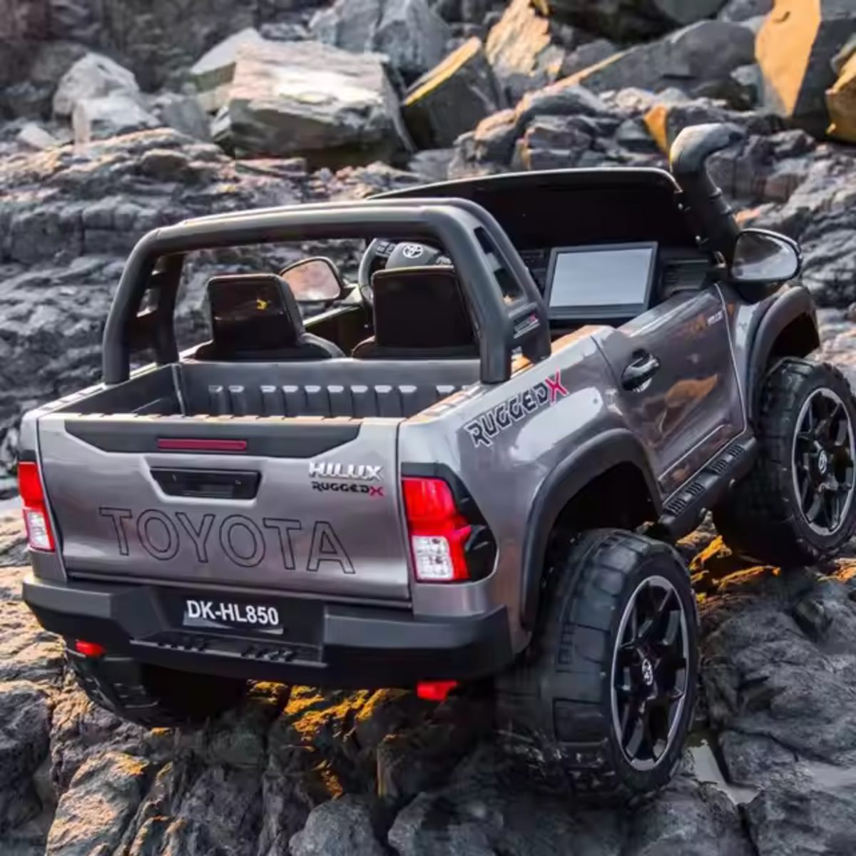 Spray painted grey 24V Toyota Hilux 4WD ride-on car for kids with realistic design and rugged off-road tires.