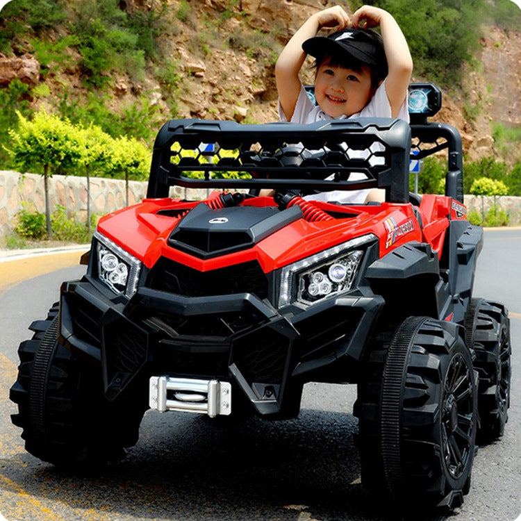 Child smiling and playing in a red 12v electric ride-on buggy car on a paved road outdoors