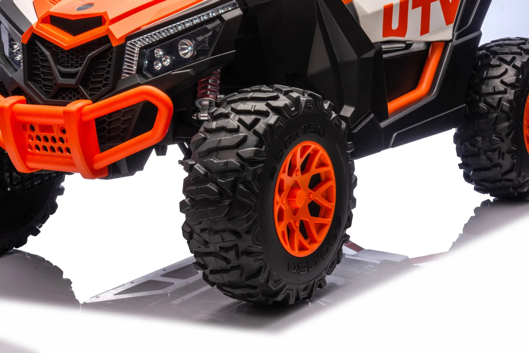 Close-up of front orange wheel and rugged tire tread on King of UTVs ZForce RZR Turbo 24V ride-on buggy for kids.