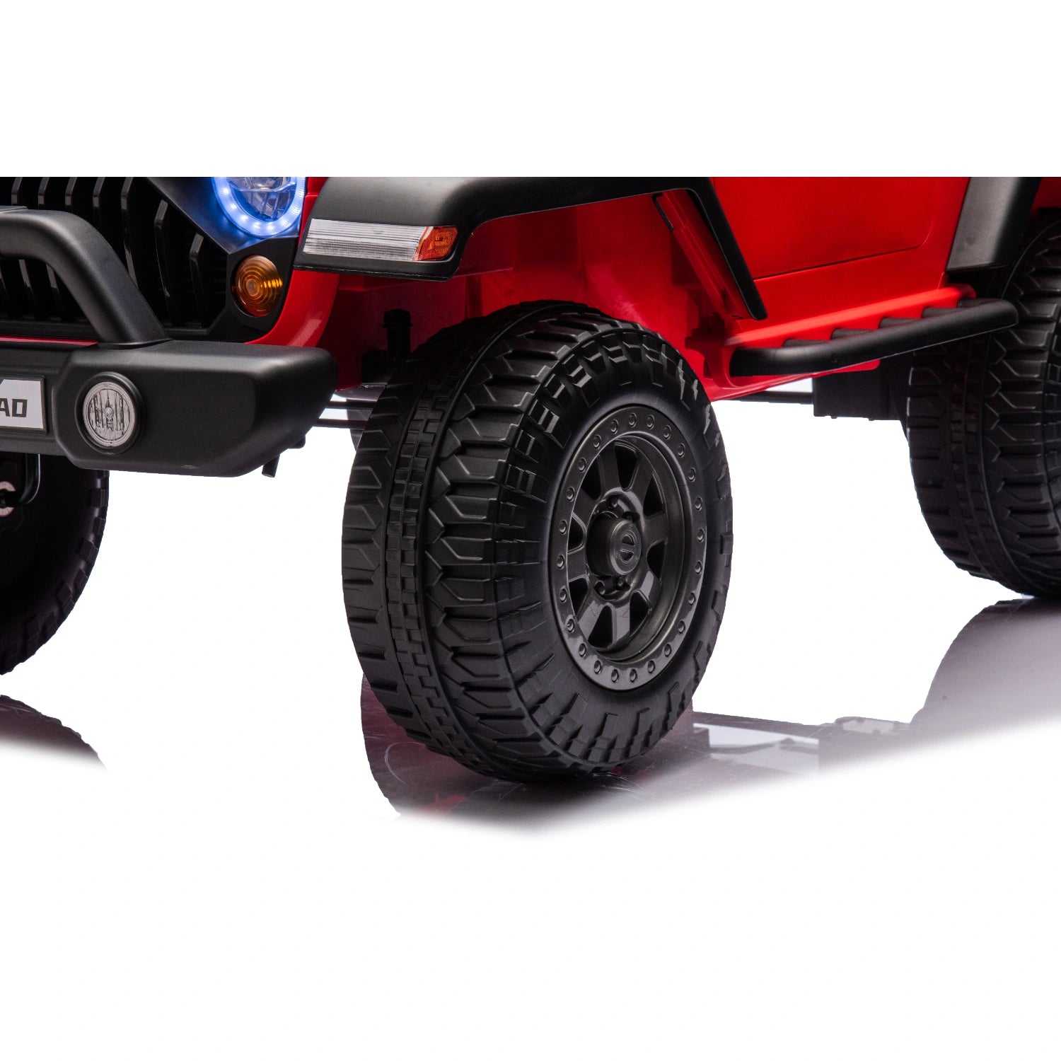 Close-up of rugged black front wheel and tire on red 12V off-road electric Jeep ride-on car for kids