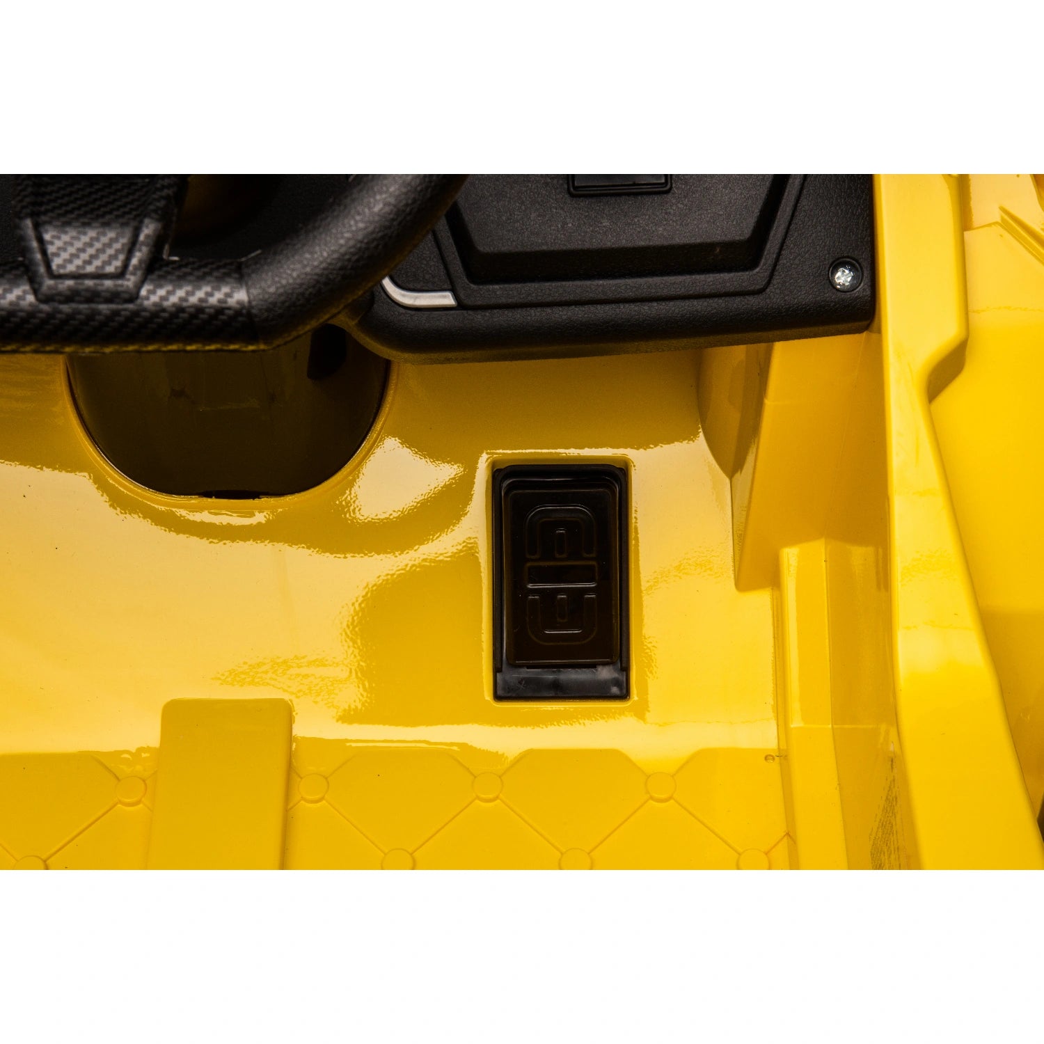 Close-up of black on/off switch panel and yellow floorboard with diamond pattern on 12V Lamborghini kids ride-on car