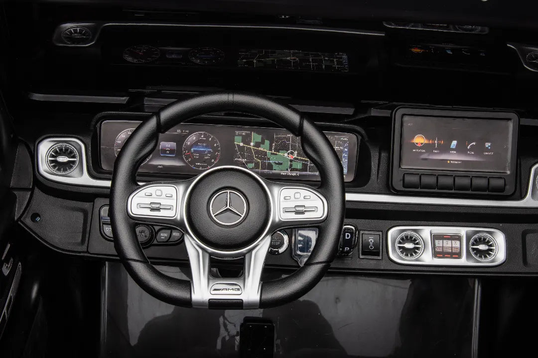 Close-up of black Mercedes-AMG G63 24V kids ride-on car steering wheel and digital dashboard with control buttons