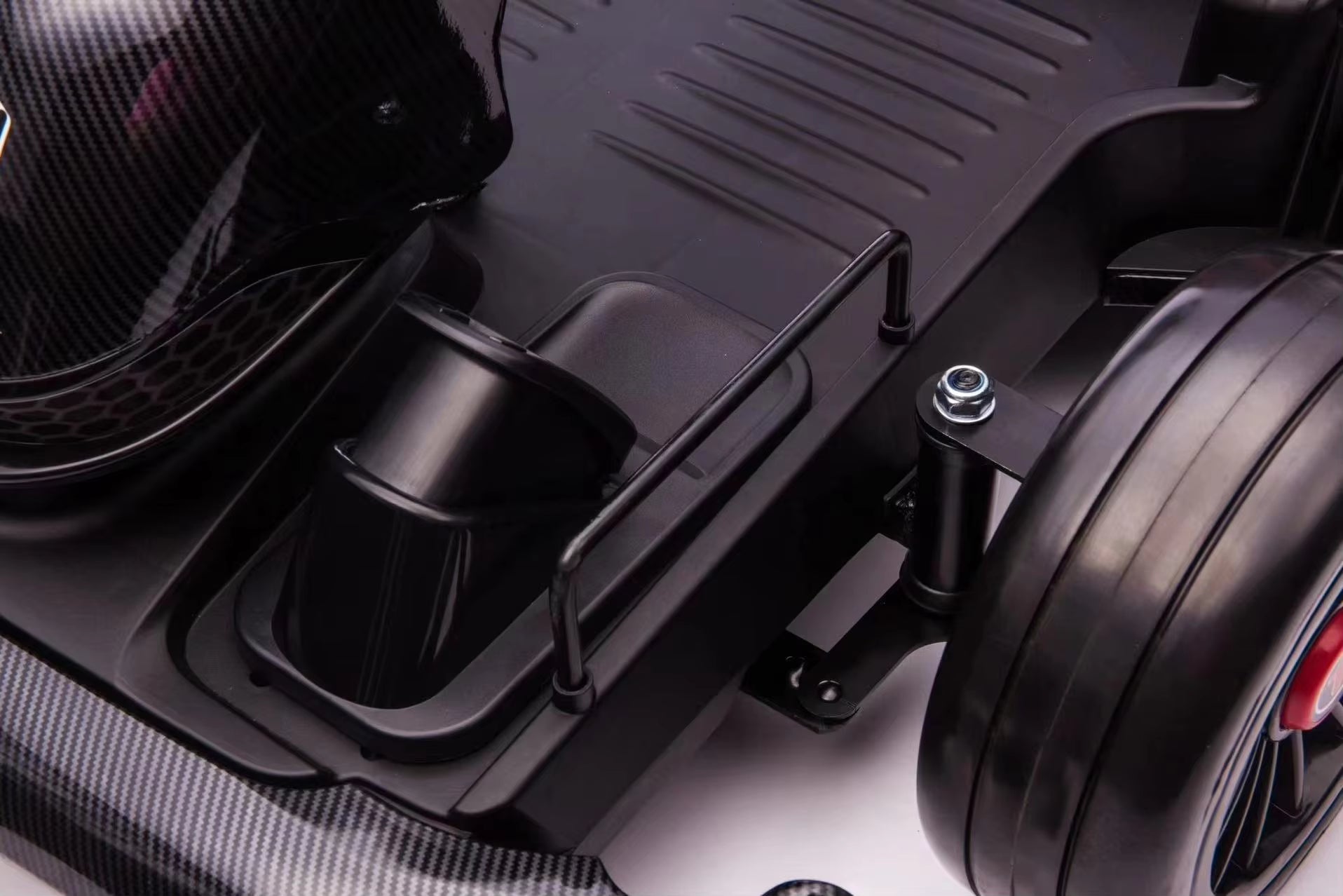 Close-up of black footrest, chassis, and rear wheel of pink 24V electric kids go-kart with drift function and motors