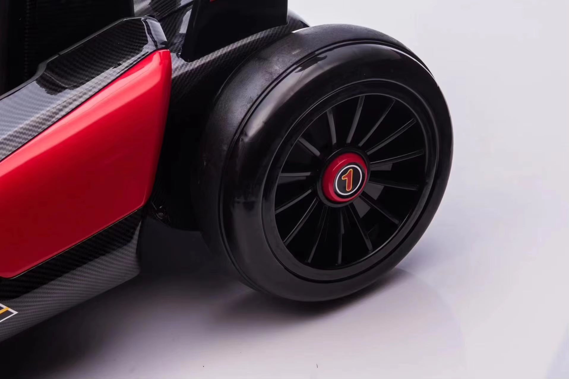 Close-up of black front wheel with number one badge on pink 24V electric kids go-kart motorsport with drift function