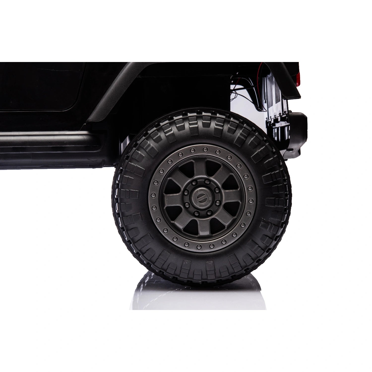 Close-up of rugged black off-road tire and rim on 12V Jeep style ride-on toy car for kids with remote control