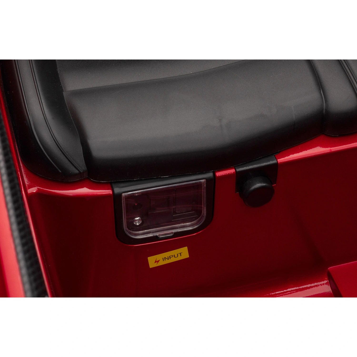 Close-up of red Lamborghini Veneno ride-on car interior showing black seat and battery input port with cover.