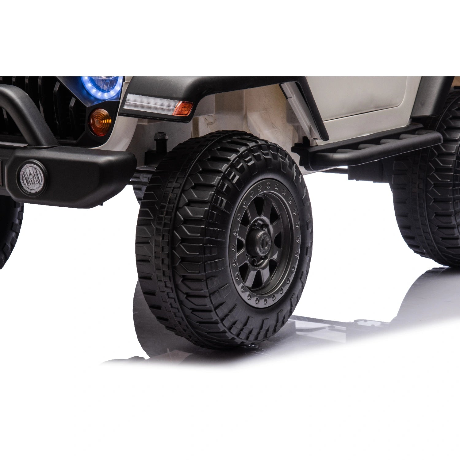 Close-up of black rugged front wheel and tire on white 12V ride-on jeep style kids electric car with LED lights